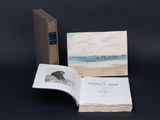 an open book sitting on top of a table next to a painting