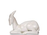 a statue of a goat laying down on a white surface