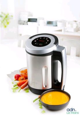 a bowl of soup next to a blender and a bowl of carrots