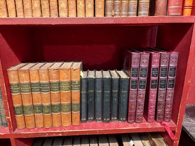 de nombreux livres anciens sur une étagère rouge dans une bibliothèque
