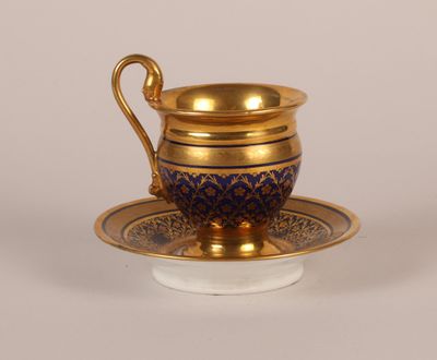 une tasse et une soucoupe dorées et bleues posées sur une soucoupe