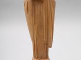 une statue représentant une femme vêtue d'une cape, les mains posées sur la tête