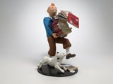 figurine représentant un homme portant une pile de livres et un chien blanc