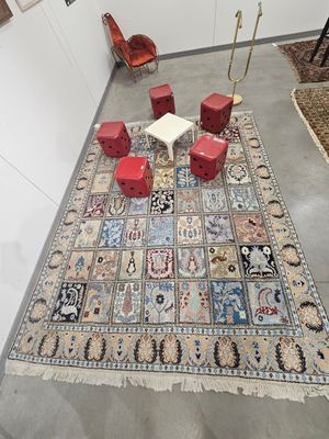 un tapis posé au sol, au milieu d'une pièce où se trouvent des tabourets rouges