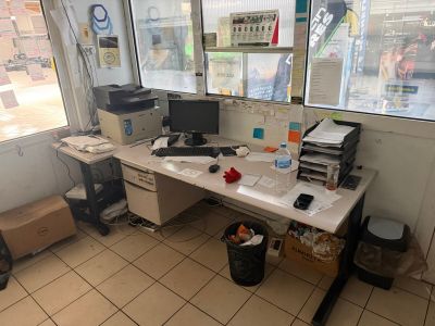 a desk with a computer and a printer in the corner of the room