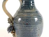 a blue vase with a handle on a white surface