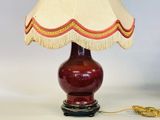 une image représentant une lampe avec un pied rouge et un abat-jour beige