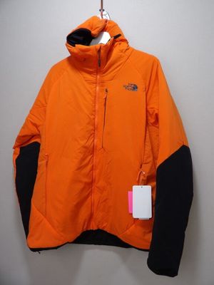 une veste orange et noire accrochée à un mur blanc