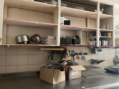 Il y a beaucoup de casseroles et de poêles sur le plan de travail de cette cuisine