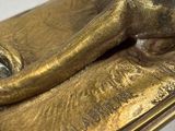 bronze statue of a cat on a gold plate with a white background