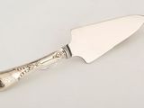 a silver plated cheese knife with a handle and a handle