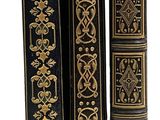 trois livres noirs et dorés sont alignés sur une surface blanche