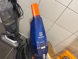 a blue and orange vacuum and a yellow tool on the floor