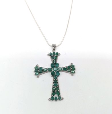 un gros plan d'un pendentif en forme de croix verte sur fond blanc