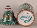 a green and white vase and a bell on a table