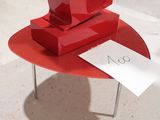 a red sculpture on a red table with a note on it