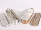 several metal pans are lined up on a white surface