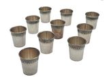six verres à shot en argent sont disposés en cercle sur un fond blanc