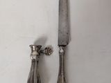 pair of antique silver plated knife and candle holders on a white table