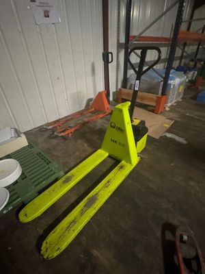 un chariot élévateur jaune garé dans un entrepôt à côté d'autres palettes