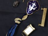une cravate bleue et dorée sur laquelle figurent une horloge et d'autres motifs, posée sur un tissu noir