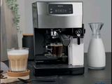 une machine à café posée sur une table, à côté d'un verre de lait