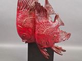 sculpture of two red fish on a black stand