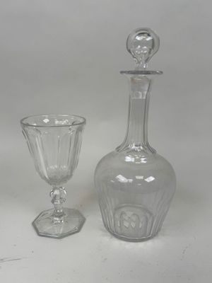 une bouteille en verre et un gobelet en verre posés l'un à côté de l'autre