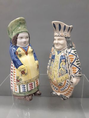 two ceramic figurines of a man and a woman standing next to each other
