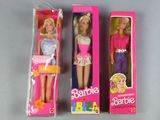 three barbie dolls are in a pink box on a table