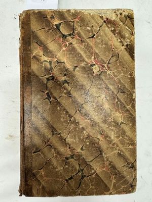 un vieux livre posé sur une table à côté d'une feuille de papier