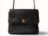 un sac Chanel noir avec des finitions dorées sur la poignée