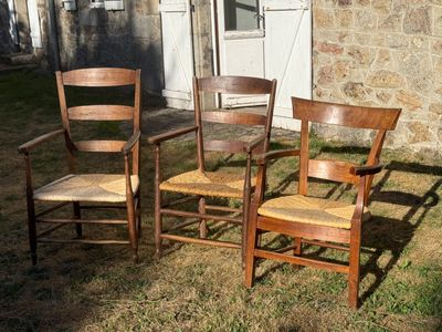 three chairs that are sitting in the grass near a building