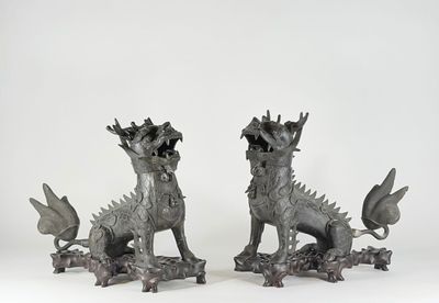 une paire de statues en bronze représentant un dragon et un chien sur fond blanc