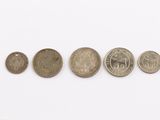 five different coins are arranged in a row on a white surface