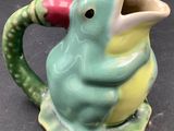 a green and yellow bird shaped pitcher with a red beak