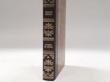 an old book sitting on top of a white table next to a glass