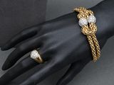 a close up of a person ' s hand wearing a gold bracelet and a diamond ring