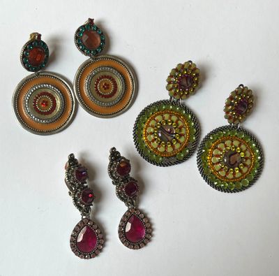 three pairs of earrings are sitting on a white surface
