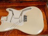 a white guitar in a wooden case on a table