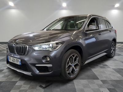 the bmw x1 is parked in a showroom with a checkered floor
