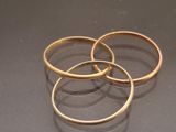 three gold rings on a table with a black background