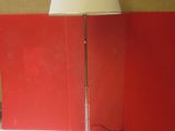 une lampe posée sur une table, avec un mur rouge en arrière-plan