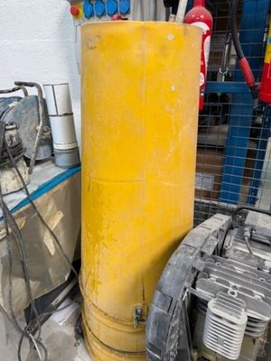 un grand réservoir jaune posé à côté de deux compresseurs d'air