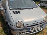 a small silver car parked in the grass next to a trailer