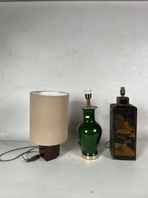 trois vases verts et une lampe posés sur une surface blanche