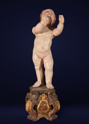 une statue ancienne représentant un bébé sur un socle, avec une horloge en arrière-plan
