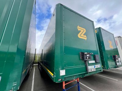 two large green trailers parked in a parking lot