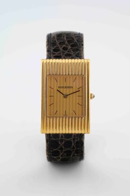 a close up of a gold watch with a black leather band