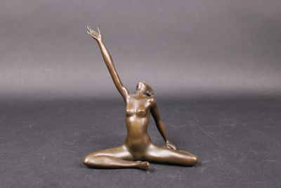 statue représentant une femme assise par terre, les bras levés vers le ciel